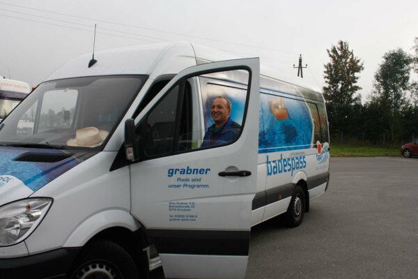 Cranpool Service oder Cranpool Montagebus, vor dem Bus steht ein Cranpool Mitarbeiter, welcher die Türe Öffnet. Der Service/ MOntagebus steht am Cranpool Parkplatz