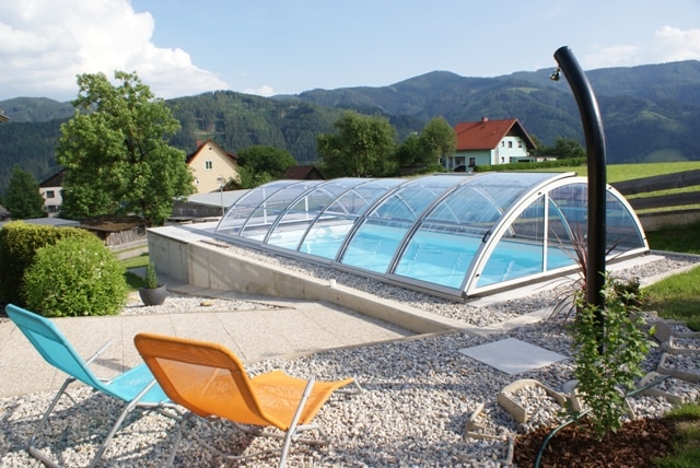 Cranpool Cranthermo mit geschlossenem Cabriodom Klassik. Im Vordergrung ist eine Solardusche aufgebaut. Zwei Liegestühle laden zu erholsamen Stunden am Schwimmbecken ein.