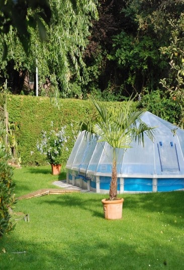 Stahlwand-Swimmingpool Royal von Cranpool, ein ovales Becken mit Sonnendom. Es wurde teilversenkt ins Erdreich.