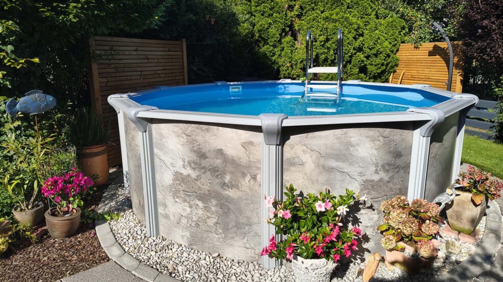 Rimini Pool rund mit Poolverkleidung im Kiesbett und Blumen