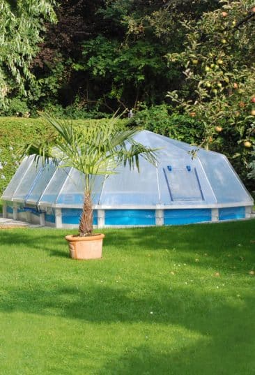 Stahlwand-Swimmingpool Royal von Cranpool, ein ovales Becken mit Sonnendom. Es wurde teilversenkt ins Erdreich.