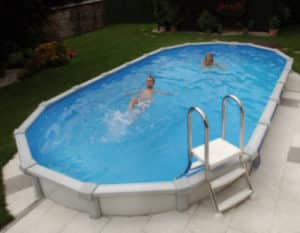 ein ovales Schwimmbecken in einem Garten. In dem Cranpool Pool sine zwei junge menschen, welche den Pool genießen