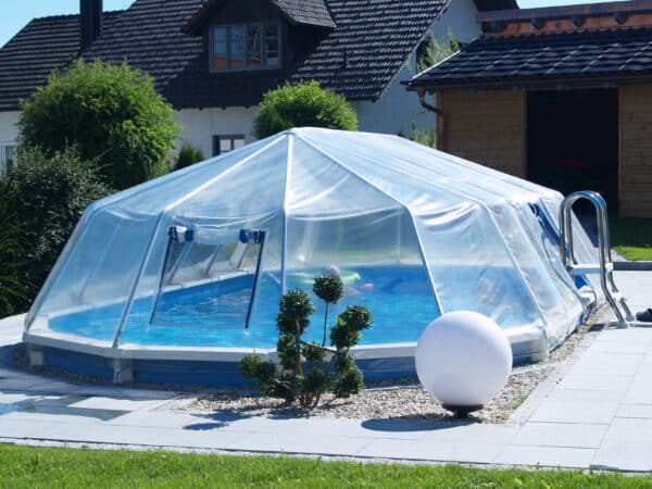 ein eingegrabenes Stahlwnd Schwimmbecken von Cranpool mit einen Sonnendom und einer umrandung aus Steinen