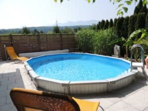 Das ovale Stahlwandschwimmbecken von Cranpool ist ein teilweise eingegrabenes Pool, welches eine weiße Schwimmbadverkleidung hat. Auch gibt es eine Leiter mit weißen Sprossen in das Pool hinein.