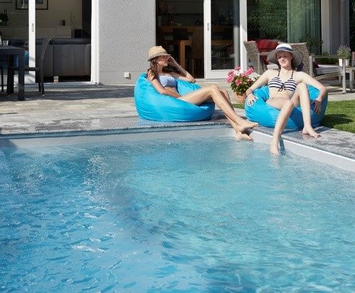 Cranpool Schwimmbecken rechteckig, eingegraben, mit zwei jungen Mädchen welche auf Sitzsäcken sitzen