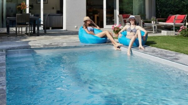 Cranpool Schwimmbecken rechteckig, eingegraben, mit zwei jungen Mädchen welche auf Sitzsäcken sitzen