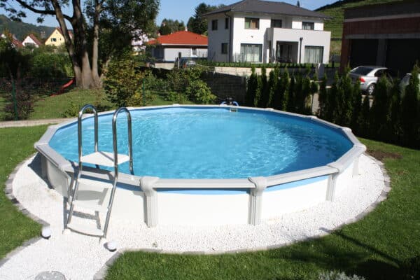 freistehender runder Pool mit Leiter in einem Garten. Das Schwimmbecken hat eine Verkleidung basic.