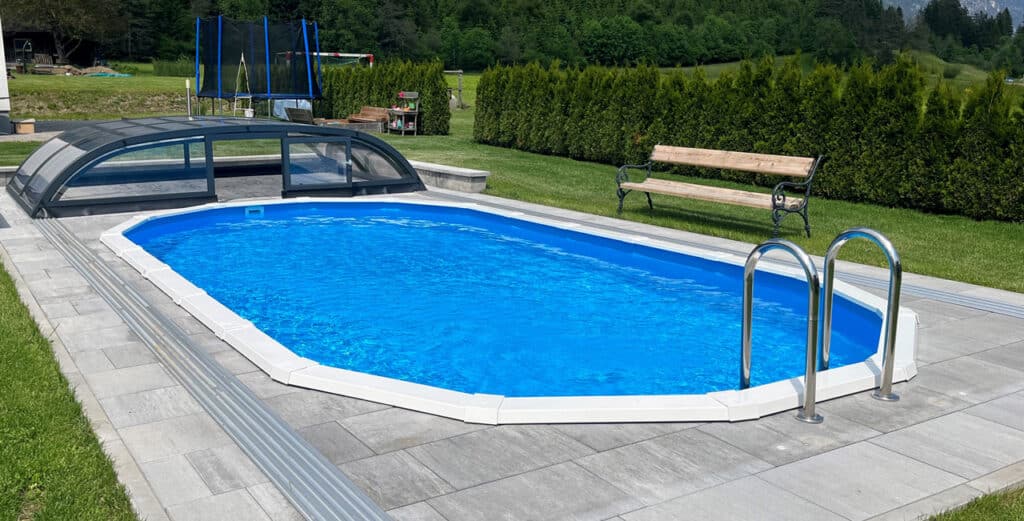 Ovales Pool versenkt mit Leiter und Poolüberdachung und Steinpflasterung