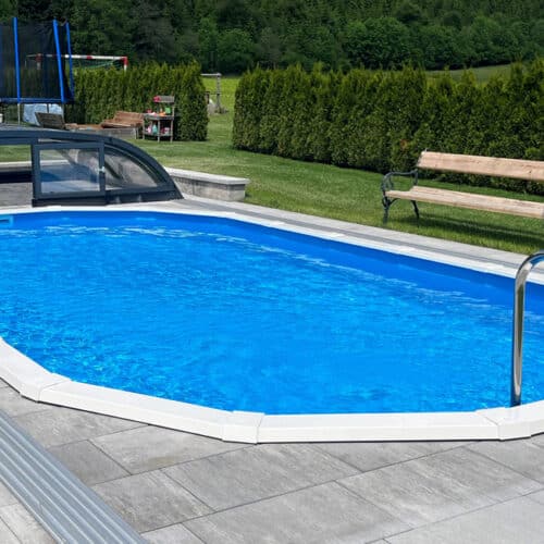 Ovales Pool versenkt mit Leiter und Poolüberdachung und Steinpflasterung