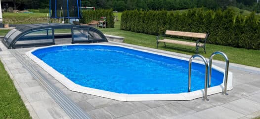 Ovales Pool versenkt mit Leiter und Poolüberdachung und Steinpflasterung