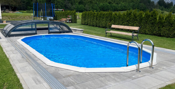 Ovales Pool versenkt mit Leiter und Poolüberdachung und Steinpflasterung