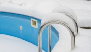 ein schwimmbecken im Winter, welches dem Frost und den Niederschlägen ohne den Schutz einer Winterabdeckplane ausgesetzt ist