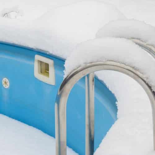 ein schwimmbecken im Winter, welches dem Frost und den Niederschlägen ohne den Schutz einer Winterabdeckplane ausgesetzt ist