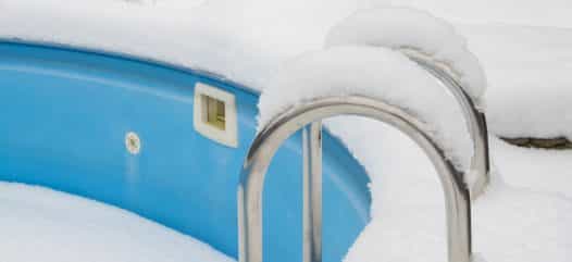 ein schwimmbecken im Winter, welches dem Frost und den Niederschlägen ohne den Schutz einer Winterabdeckplane ausgesetzt ist