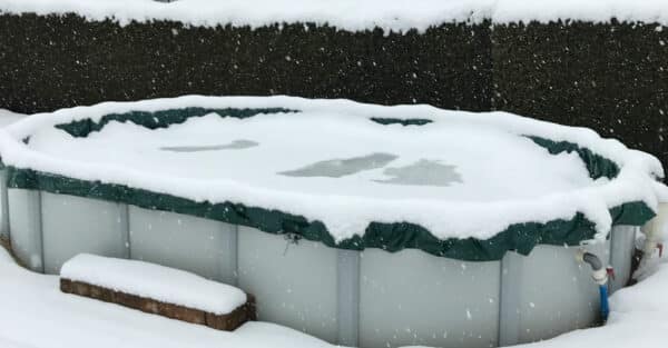 ein ovales Schwimmbecken im Winter. DAS Pool ist vvon einre Winterabdeckplane von Cranpool gegen den Niederschlag und den Frost geschützt.