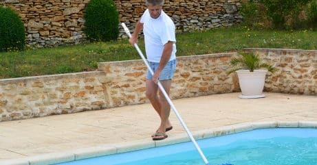ein stolzer Cranpool Poolbesitzer beim reinigen seines rechteckigen Beckens mit einem kescher