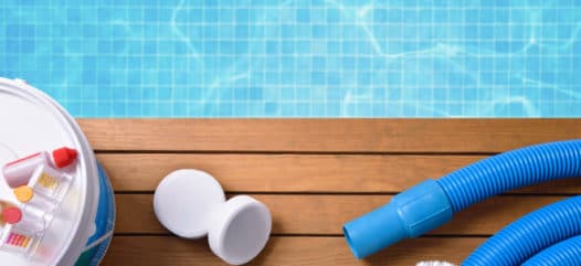 reinigung der Zusatzprodukte am pool Chemical products and tools for the maintenance of the pool on wooden slats. Pool with water and blue mosaics background. Horizontal composition. Top view