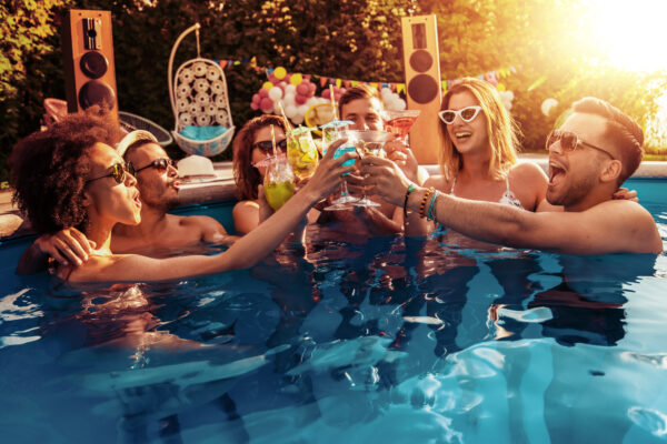 Friends having party and dancing in swimming pool. Enjoying in cocktails. eine Gruppe von jungen Erwachsenen bei einer Pool apsryt mit farbenfrohen Geträmken und einem Sonnen untergang