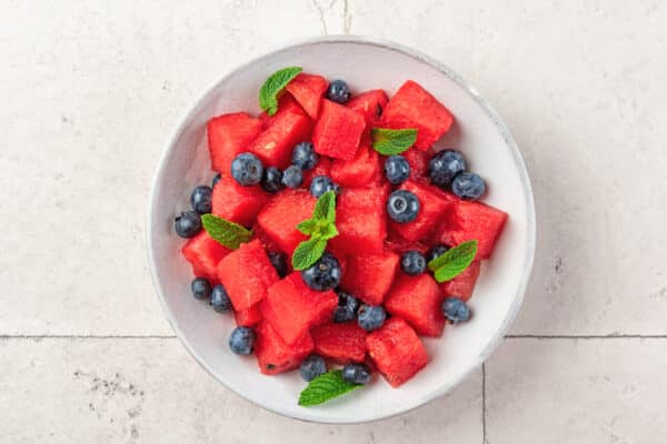 Watermelon salad with blueberries and mint in a plate on white table. Top view. Healthy summer vegetarian dessert