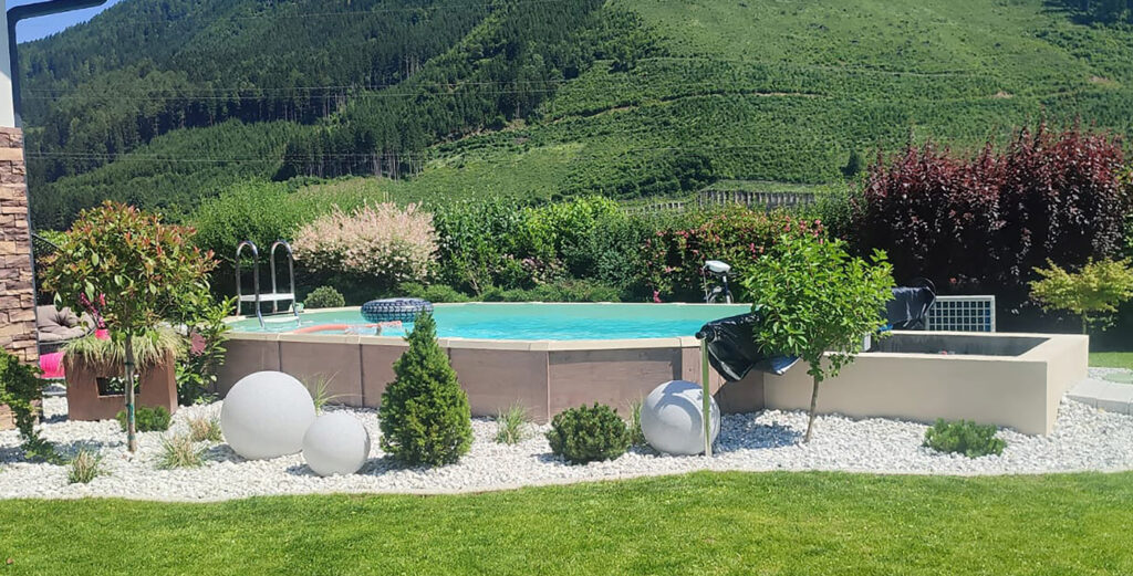 Schwimmbecken royal mit Poolverkleidung in Holzdekor seitlich im Kiesbett
