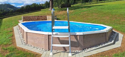 Ovales Pool mit Holzverkleidung in Hanglage und Leiter