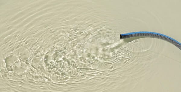 Gartenschlauch mit fließendem Wasser im Pool