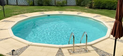 Versenkter Grand Royal Rundpool mit Einstiegstreppe und gepflasterter Poolumrandung im privaten Garten.